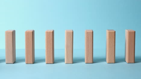 Domino-effect,-row-of-wooden-domino-falling-down-with-blue-background