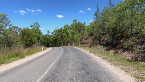 Rear-facing-driving-point-of-view-POV-of-a-deserted-dry-dusty-Queensland-country-road-with-gum-trees-and-rocky-banks---ideal-for-interior-car-scene-green-screen-replacement
