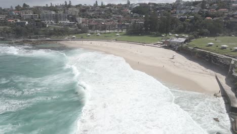 Foamy-Ocean-Waves-Washing-Ashore---Scenic-View-Of-Bronte-Beach-In-Eastern-Suburbs,-Sydney,-New-South-Wales,-Australia---aerial-drone-shot