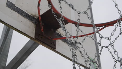 Metallic-net-of-an-old-basketball-hoop,-handheld-dramatic-shot