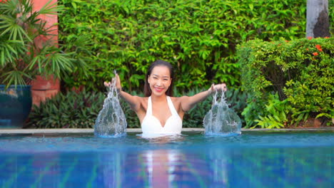 A-playful-young-woman-splashes-pool-water