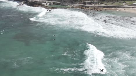 Menschen-Auf-Ihren-Surfbrettern-Treiben-Durch-Brechende-Wellen-Am-Bronte-Beach-Mit-Bronte-Baths-In-Sydney,-Australien