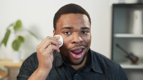 portrait-of-a-dark-skinned-man-wiping-his-face-with-a-cotton-pad