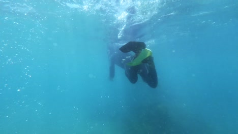 A-scuba-diver-kicks-up-water-causing-bubbles-in-crystal-clear-blue-water-in-Maracajau-in-Rio-Grande-do-Norte,-Brazil