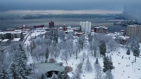 Aerial-flyover-snowy-Wright-Park-with-many-people-having-fun-in-snow-During-Winter-In-Tacoma,-Washington