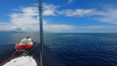 POV-shot-out-front-of-small-boat-cruising-towards-distant-tropical-island
