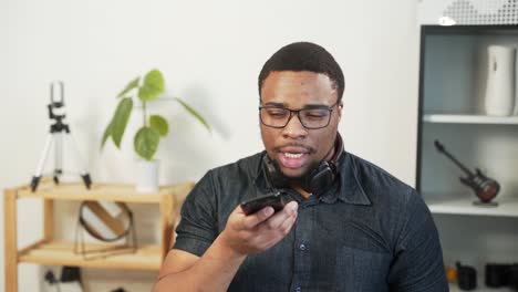 Hombre-Negro-Carismático-Graba-Un-Mensaje-De-Voz-En-Un-Teléfono-Inteligente