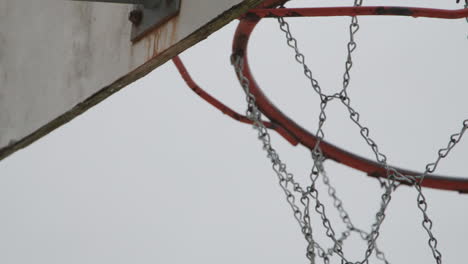 Close-up-of-old-metallic-basketball-hoop-net,-handheld-and-slow-motion