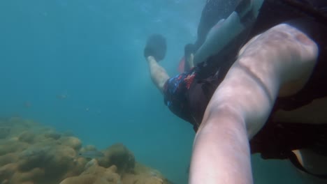A-tourist-on-vacation-scuba-diving-holding-a-GoPro-towards-themselves-as-they-swim-through-crystal-clear-blue-water-of-Maracajau-in-Rio-Grande-do-Norte,-Brazil