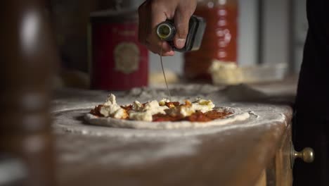 Würzen-Olivenöl-Rohe-Hausgemachte-Käsepizza-In-Zeitlupe-60fps-Auf-Holztisch