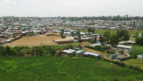 Cityscape-of-the-slums-of-kibera-kenya,-poor-family-playing-around-the-the-empty-football-pitch,-over-population-in-the-slums-of-kibera-kenya