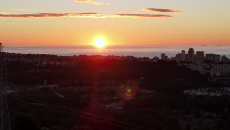 Panning-drone-footage-of-a-stunning-yellow-and-orange-sunrise-over-the-Mediterranean-sea-on-a-clear-morning,-with-the-town-of-Calpe,-Spain-in-the-foreground