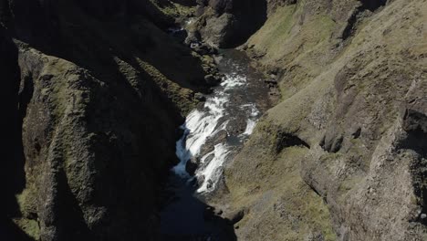 Aerial-at-canyon-of-Stjornarfoss-waterfall-in-between-volcanic-cliffs,-Iceland