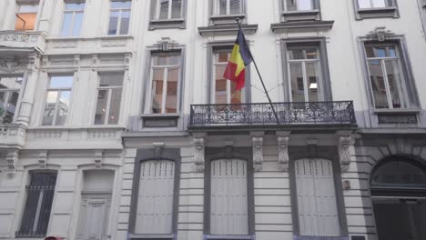 Bandera-Belga-Ondeando-En-Un-Balcón-En-Bruselas,-Bélgica,-Tiro-Ancho-De-ángulo-Bajo