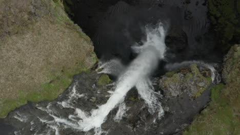 Above-powerful-Kvernufoss-waterfall,-water-falling-over-edge-of-cliff,-aerial