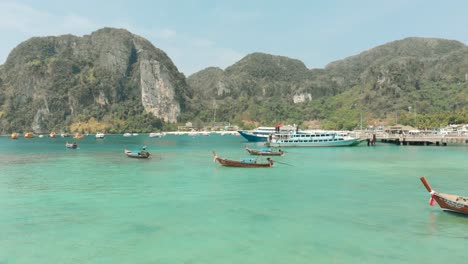 Idyllische-Smaragdgrüne-Meerwasser-Tonsai-Bucht-Mit-Einer-Gruppe-Von-Angedockten-Langheckbooten-Auf-Der-Insel-Ko-Phi-Phi-Don-In-Thailand---Luftaufnahme-Mit-Niedriger-Überführung
