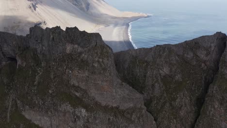 Reveal-shot-of-coastal-land-in-Iceland-behind-Krossanesfjall-ridge,-aerial