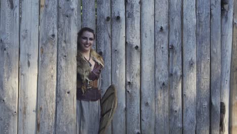 Happy-viking-girl-with-sword-and-shield-peeking-out-of-hte-gate-and-hiding