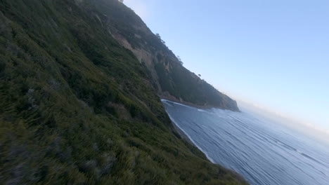 Following-the-contours-of-the-landscape-along-the-cliffs-overlooking-the-beach-in-a-first-person-view-racing-drone