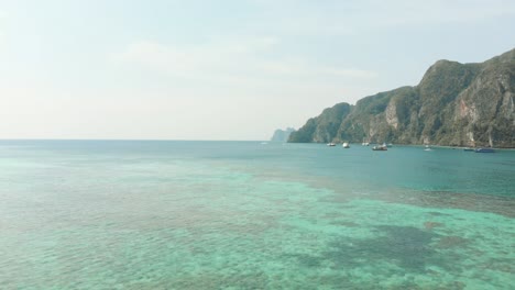 Mar-Verde-Esmeralda-Cálido-Y-Poco-Profundo-Que-Cubre-La-Inmensidad-De-La-Costa-De-La-Isla-De-Ko-Phi-Phi-Don-En-Tailandia---Toma-Aérea-Hacia-Atrás