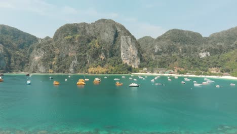 Tonsai-Bay-unspoilt-exotic-paradise-harbouring-fleet-of-small-boats-in-Ko-Phi-Phi-Don-Island,-Thailand---Aerial-Fly-over-shot