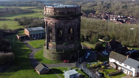 Aerial-view-National-trust-Norton-water-tower-landmark-Runcorn-England-urban-countryside-scene-orbit-right