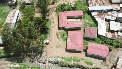 Drone-Volando-Sobre-La-Vieja-Hoja-De-Techo-De-Las-Casas-En-Los-Barrios-Marginales-De-Kenia,-Corriente-De-Agua-Contaminada-En-Los-Barrios-Marginales-De-Kibera-Kenia