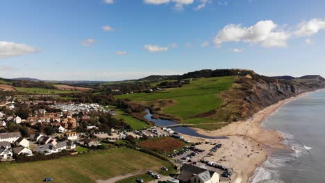 Aerial-rising-shot-with-a-view-looking-over-Charmouth-towards-the-Cliffs-and-Beach-in-Dorset-England-UK
