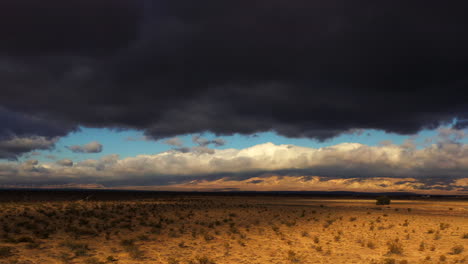 Dramatic-dark-rain-clouds-gather-for-a-storm-above-the-Mojave-Desert---aerial-view