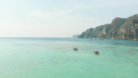 Abundant-Turquoise-exotic-waters-stretching-beyond-the-horizon-encircled-by-Ko-Phi-Phi-Don-Island-Paradise-in-Thailand---Aerial-Low-Panoramic-shot