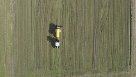 Top-down-aerial-of-tractor-fertilizing-large-field