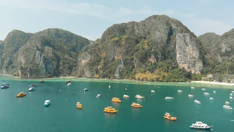 Picturesque-scenic-view-of-large-bay-crowded-with-moored-boats-in-Ko-Phi-Phi-Don-Island-Paradise-in-Thailand---Aerial-Fly-over-panoramic-shot