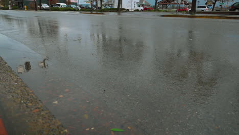Reflection-Of-Car-Driving-By-Puddle-On-The-Road-On-A-Rainy-Day---Low-Level-Shot,-Closeup