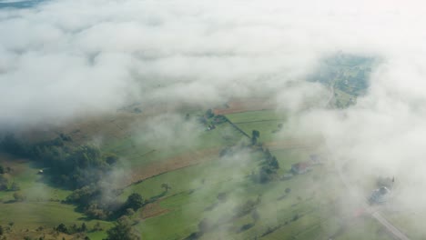 Aerial-shot-looking-down-through-the-clouds-to-the-rural-landscape-below