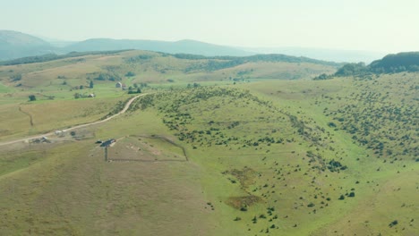 Aerial-View-Of-Green-Hills-With-Fence-On-Countryside-Farm-In-Summertime