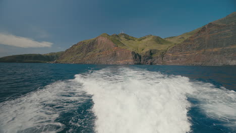 Boat-wake-with-scenic-mountainous-cliffs-of-Madeira,-waves-behind-yacht