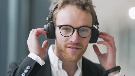 Portrait-of-a-stylish-young-man-in-headphones-and-glasses