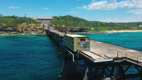Disused-old-coal-loading-pier-on-secluded-Australia-coast,-aerial-view
