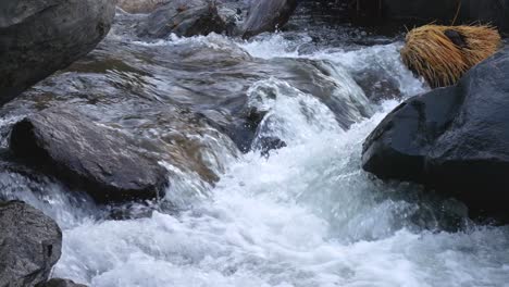 White-water-rushing-in-between-rocks-and-boulders-down-a-creek---close-up