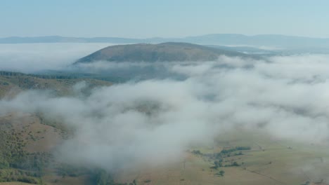 Aerial-flyover-shot-high-above-the-clouds-looking-out-on-a-pastoral-landscape