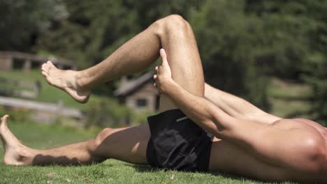 4K-Young-caucasian-fit-attractive-male-exersicing-outdoors-with-green-vegetation-background-hamstrings-mobility-exercise-2