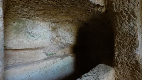 Close-up-pullback-of-looking-deep-inside-the-dark-burial-chambers-in-the-Tomb-of-the-Kings-in-Paphos,-Cyprus