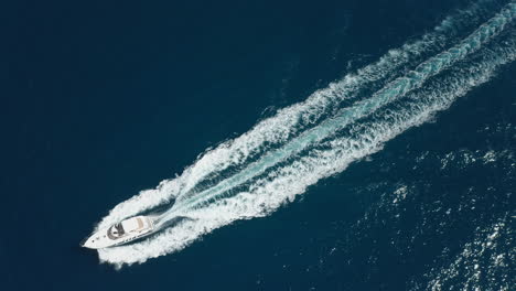 Large-yacht-travels-across-blue-water-creating-white-backwash,-aerial