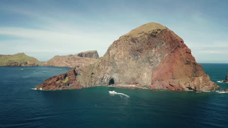 Aerial-at-Ponta-do-Furado,-steep-cliffs-of-Madeira-shore-with-boat