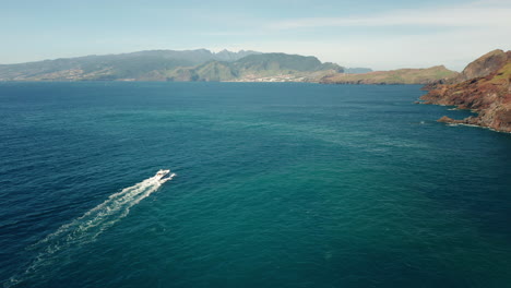 Yacht-travels-in-stunning-turquoise-water-near-shore-of-Madeira,-aerial