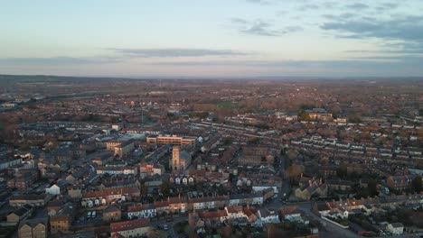 4K-aerial-view-of-the-sun-setting-over-taunton-Somerset,-United-Kingdom,-drone-moving-forward-and-showing-the-blue-sky-with-some-clouds