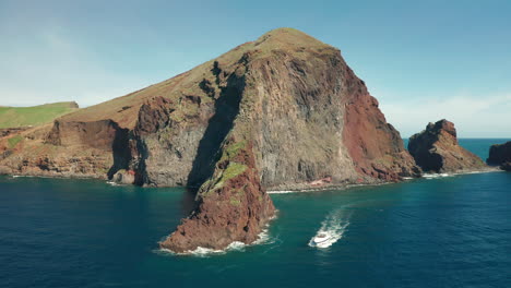 Spectacular-volcanic-shoreline-of-Madeira-with-boat-exploring-rocky-cliffs