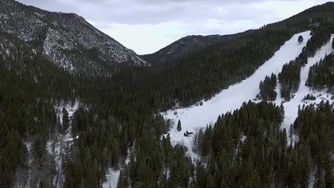 AERIAL---Camera-pulls-back-from-deep-mountain-canyon-covered-in-trees-and-snow