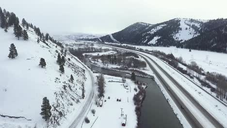 AERIAL---Camera-dolly's-above-river-and-highway-during-a-snowstorm