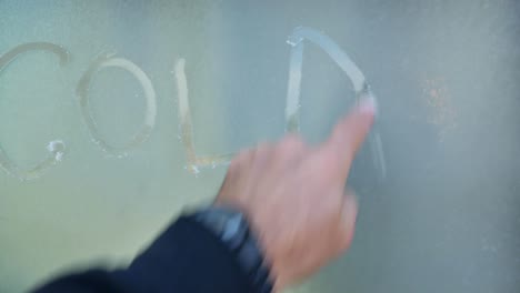 Der-Finger-Des-Mannes-Schreibt-An-Einem-Lebhaften-Morgen-Das-Wort-Kälte-Auf-Den-Fensterfrost